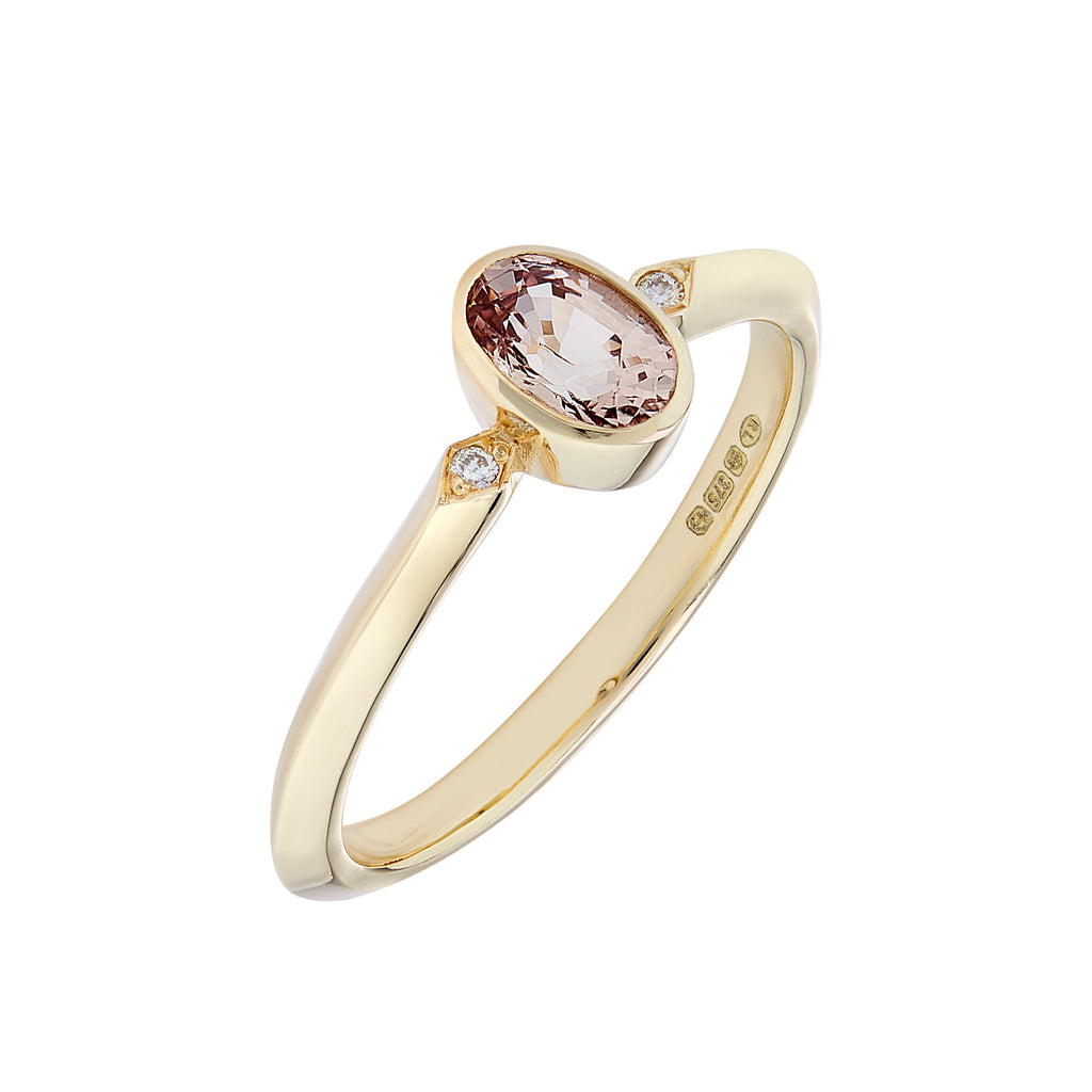 Oval peach coloured sapphire engagement ring with diamonds  